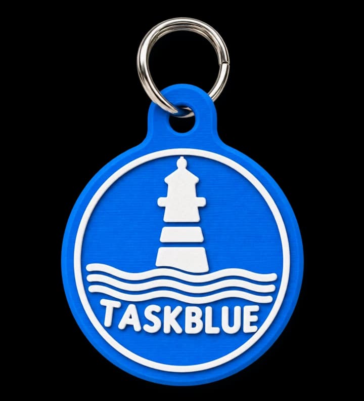 Der BlueTag: runder blauer Schlüsselanhänger mit weißem Leuchtturm und dem Schriftzug TaskBlue